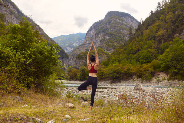 Lekce jógy v přírodě. Žena dělá jógu v horách, poblíž horské řeky teče. Koncept provozování sportu sám. Sociální vyloučení - Fotografie, Obrázek