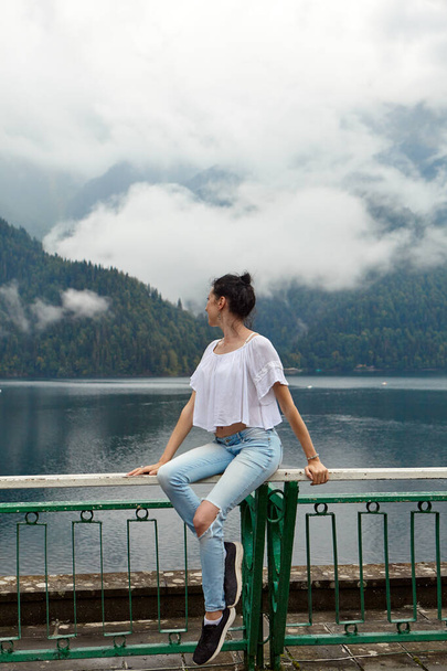 Девушка в белой одежде на фоне горного озера с голубой водой и гор с облаками. Фон. - Фото, изображение