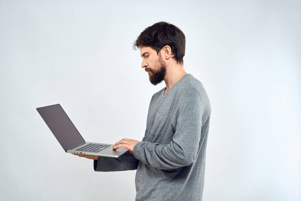 Ένας άνθρωπος σε ένα γκρι πουλόβερ με ένα φορητό υπολογιστή χέρια lifestyle τεχνολογία επικοινωνίας Internet εργασίας - Φωτογραφία, εικόνα