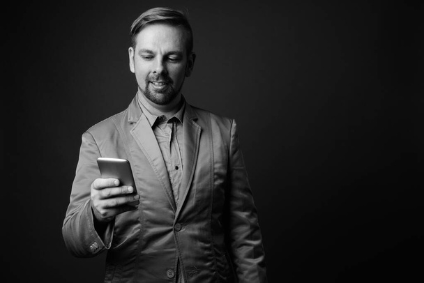 Estudio de hombre de negocios barbudo rubio con perilla sobre fondo gris en blanco y negro - Foto, Imagen