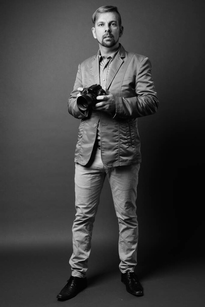 Студия фотографии блондинка бородатый бизнесмен с козлиной бородкой на сером фоне в черно-белом - Фото, изображение