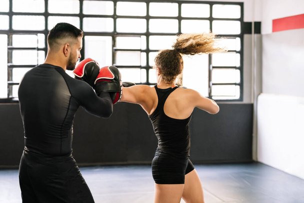 赤のボクシンググローブを身に着けている彼女の高濃度のトレーナーと女性ボクサートレーニングジムでトレーナーの手で直接パンチと肘 - 写真・画像