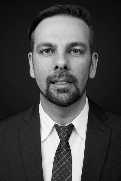 Studio shot of blond bearded businessman with goatee against gray background in black and white - Foto, immagini