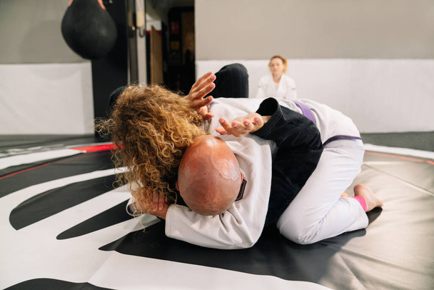 два бойца боевых искусств дзюдо женского и мужского пола, практикующие новые техники на спортивном коврике - Фото, изображение