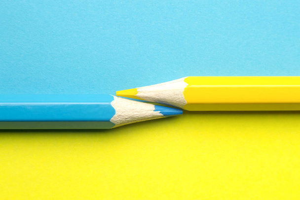 Yellow and blue pencil on blue-yellow background - Фото, зображення