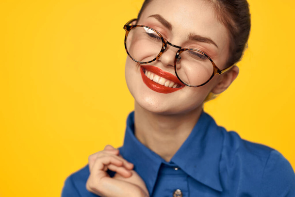 A woman in a blue shirt and glasses with bright makeup on her face is gesturing with her hands Copy Space - Foto, Imagen
