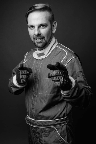 Στούντιο πλάνο του ξανθό γενειοφόρος μοτοσικλετιστής άνθρωπος με μουσάκι σε πλήρη σχέση με το γκρι φόντο σε μαύρο και άσπρο - Φωτογραφία, εικόνα