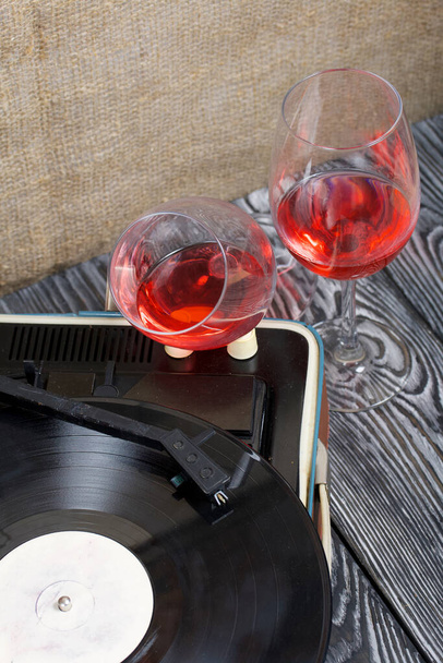 Old turntable. Nearby are two glasses of alcohol. Retro party equipment. - Foto, Bild