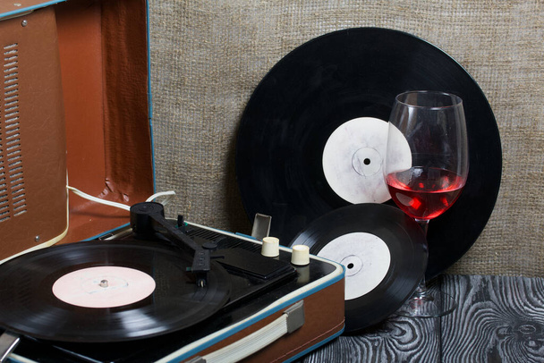 Old turntable. Nearby are two glasses of alcohol. Retro party equipment. - Foto, imagen