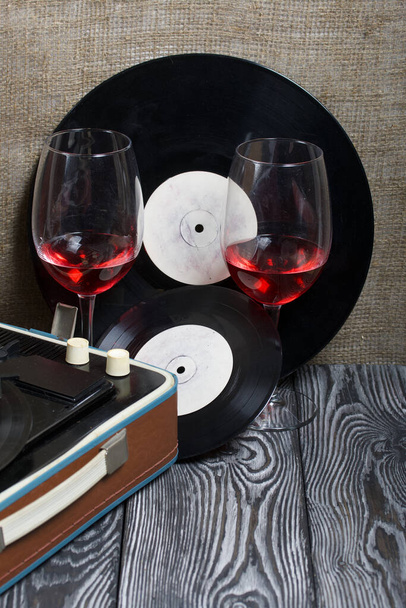 Old turntable. Nearby are two glasses of alcohol. Retro party equipment. - Фото, изображение