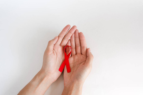 Hands holding red ribbon on white background, HIV awareness concept, World AIDS Day, World Hypertension Day, World Cancer Day. - Foto, afbeelding