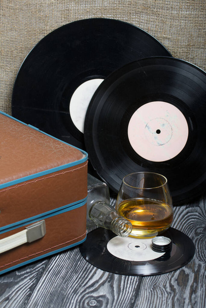 Old turntable. Nearby is a glass of strong alcohol and an empty glass bottle. Retro party equipment. - Fotografie, Obrázek