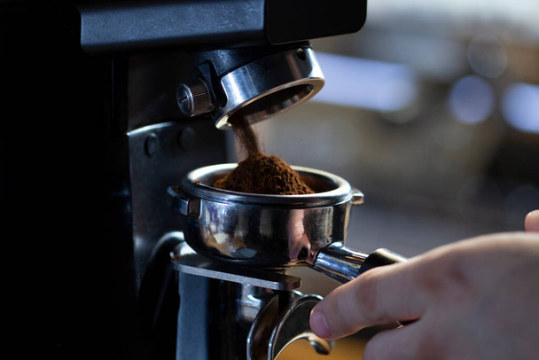 coffee grinder grinding coffee pouring into a portafilter - 写真・画像