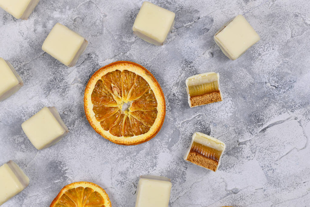 German Christmas candy called 'Dominosteine' and orange slices. A traditional food consisting of gingerbread, orange jelly and marzipan layers covered with white chocolate icing - Photo, image