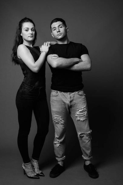 Studio shot of young couple together and in love against gray background in black and white - Foto, Imagem