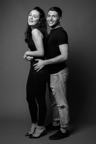 Studio shot of young couple together and in love against gray background in black and white - Фото, зображення