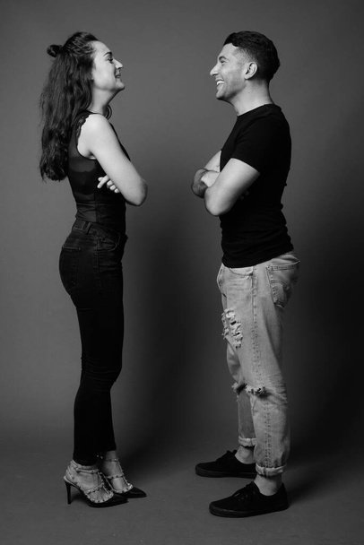 Στούντιο πλάνο του νεαρού ζευγαριού μαζί και ερωτευμένος με γκρι φόντο σε μαύρο και άσπρο - Φωτογραφία, εικόνα