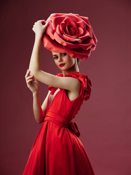  модель с декоративным цветком на голове и в красном платье - Фото, изображение