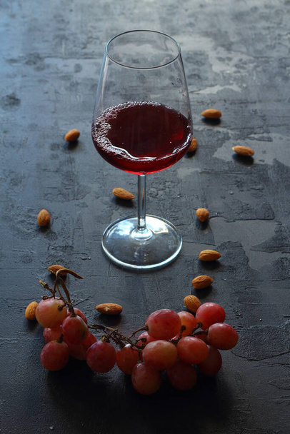 Egy pohár vörösbor az asztalon. friss szőlővel. - Fotó, kép