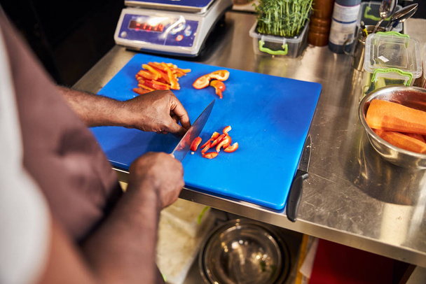 Man cutting carrot and pepper in professional kitchen - 写真・画像