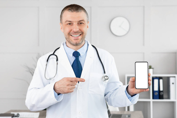 Doctor sosteniendo teléfono inteligente con pantalla blanca en blanco para maqueta - Foto, imagen