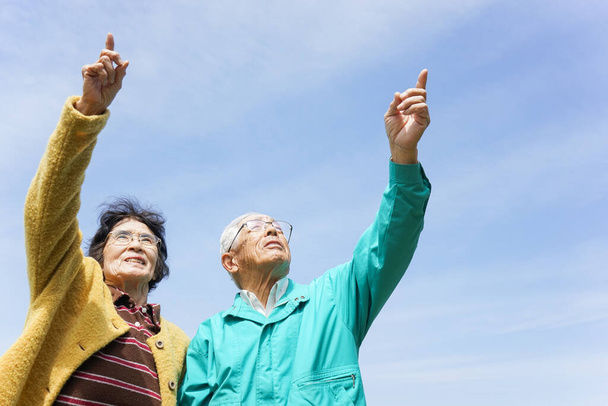Seniorenpaar zeigt bei sonnigem Tag in den Himmel - Foto, Bild