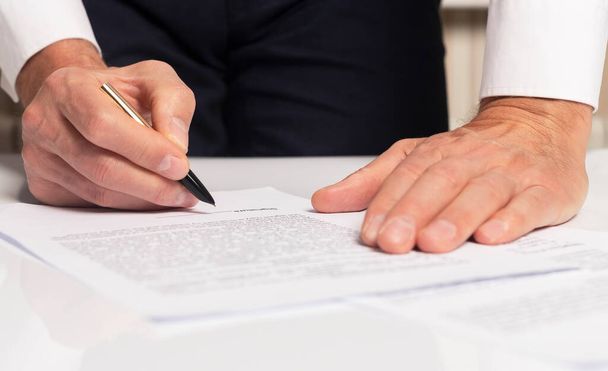 Contract signing concept. Businessman hand with pen over document closeup. - Фото, изображение