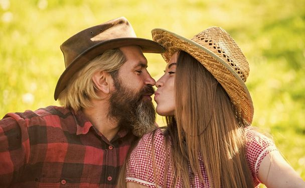 True feelings. Enjoying life. Love and harmony. Bearded cowboy in hat kissing adorable girlfriend. Couple in love. Romantic kiss. Happy couple ranch owners. Married and happy. Rustic people in love - 写真・画像