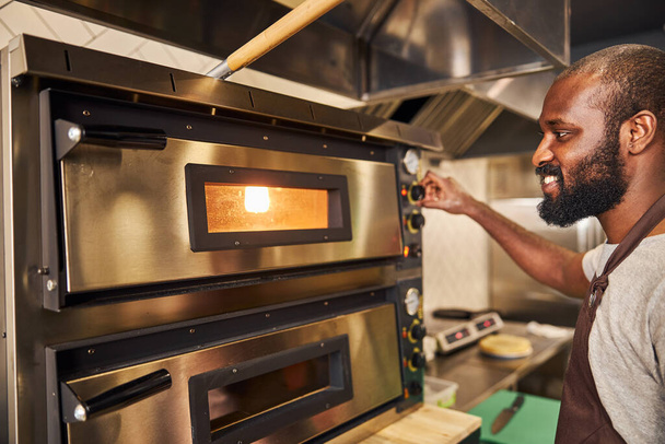 Cheerful bearded chef baking dishes in restaurant kitchen - Valokuva, kuva
