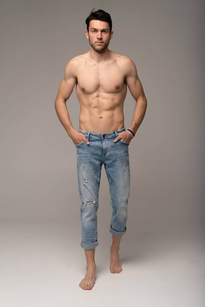 Portrait of a well built shirtless muscular male model against white background. - Foto, Imagen