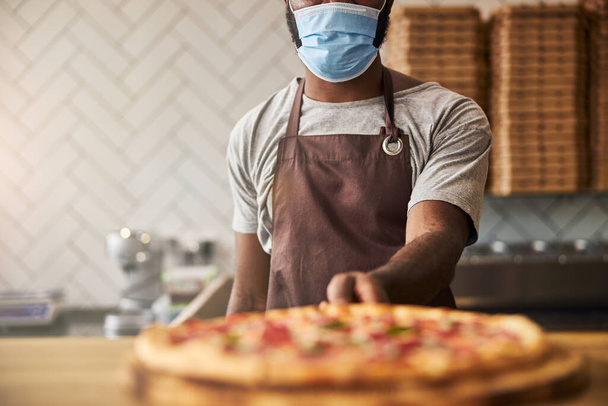 Afro American man in medical mask holding pizza - Фото, изображение