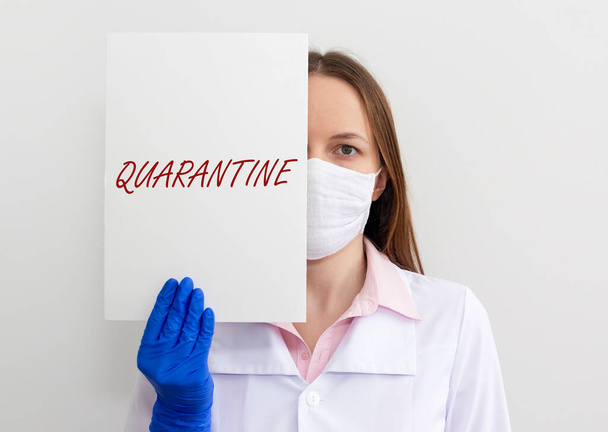 word QUARANTINE on paper in hands of doctor in protective gloves over white background. medical lockdown concept - 写真・画像