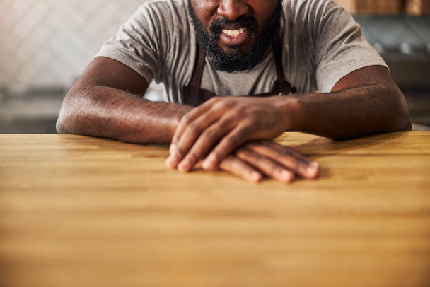 Joyful Afro American man sitting at the wooden table - Фото, зображення