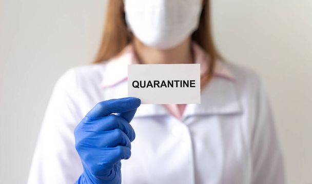 word QUARANTINE on paper in hands of doctor in protective gloves over white background. medical lockdown concept - Foto, imagen