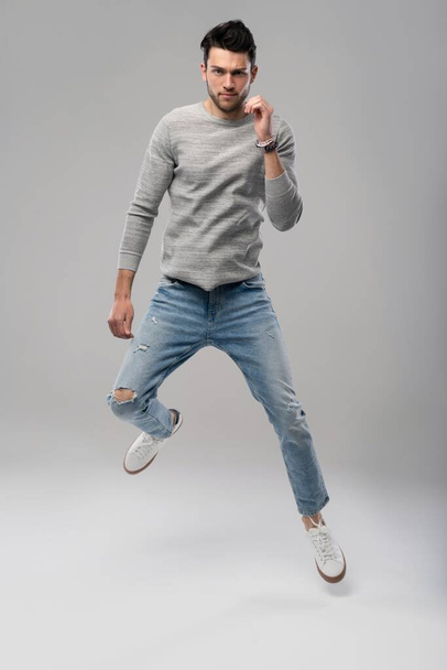 Handsome young man running or jumping in air on white background. - 写真・画像