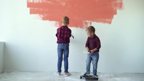 dos niños niños pintan la pared con rodillos. Concepto de renovación del hogar - Metraje, vídeo