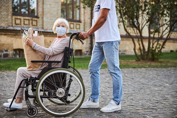 Užitečný dobrovolník chůze s tělesně postiženou osobou venku - Fotografie, Obrázek