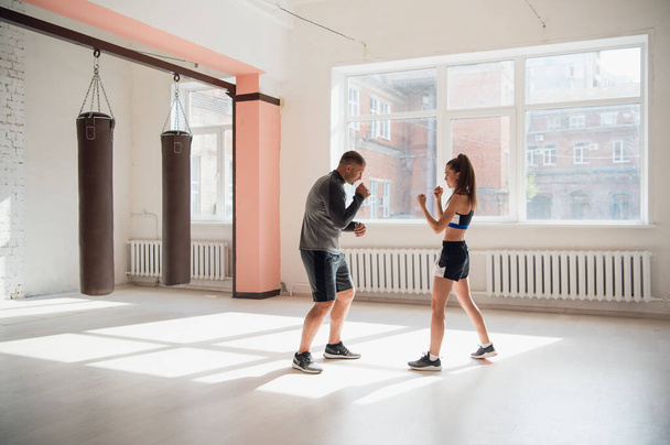Geniş bir çatı katında, bir erkek eğitmen ve kadın akıl hocası boks antrenmanı yapıyorlar. - Fotoğraf, Görsel
