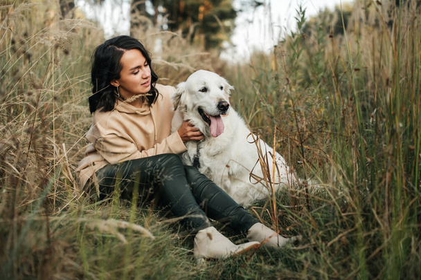 girl hugging a golden retriever dog in the field - Foto, imagen