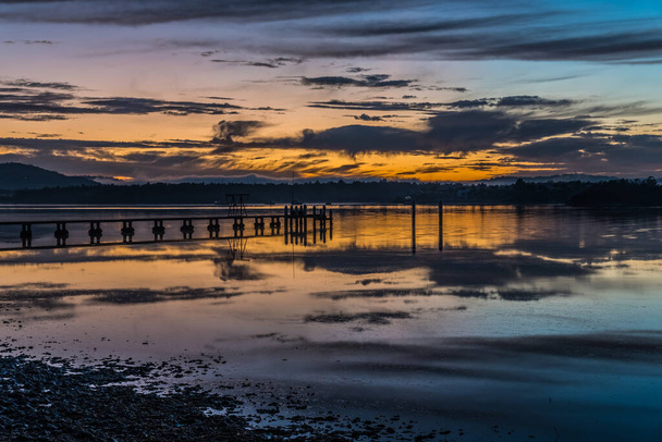 Sunrise waterscape with high cloud, wharf and reflections at Woy Woy Waterfront on the Central Coast, NSW, Australia. - Foto, Imagem