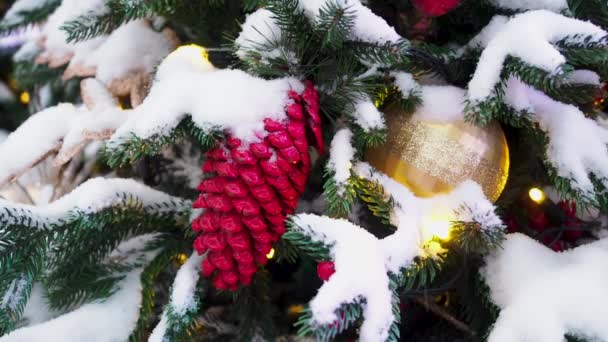 Рождественские украшения, висящие на рождественской елке, покрытые снегом на улицах города. Красивая рождественская заставка - Кадры, видео