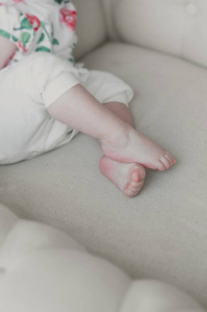vauva alasti hyvin vaaleaihoinen kalpea jalat päällekkäin kevyellä pehmeällä sohvalla - Valokuva, kuva