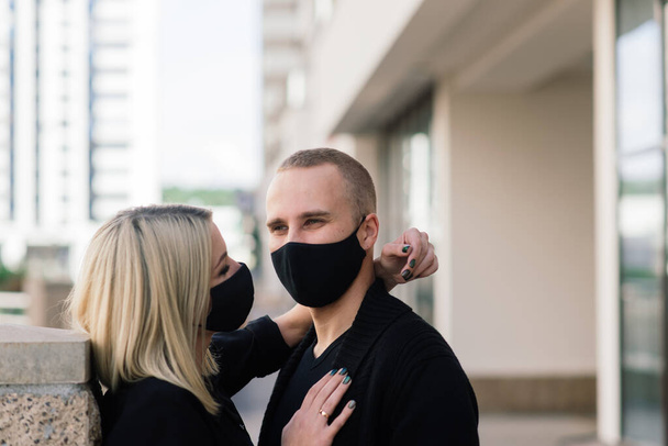Paar hippe modieuze beschermende maskers, denim jassen dragen, lopen in lege straat van de Europese stad tijdens quarantaine van coronavirus uitbraak. - Foto, afbeelding