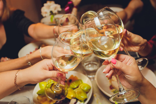 Close up shot of group of people clinking glasses with wine or champagne in front of bokeh background. older people hands. - 写真・画像