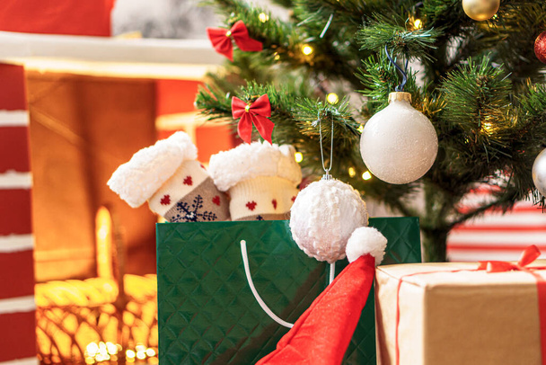 Xmas, winter, new year, Celebration, family, gift concept - Holiday atmosphere at home. Bright presents boxes under Christmas tree decorated with balls on background red fireplace with burning fire - Φωτογραφία, εικόνα