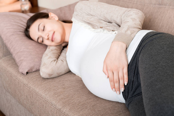 Pregnant woman relaxing at home on sofa. - Fotó, kép