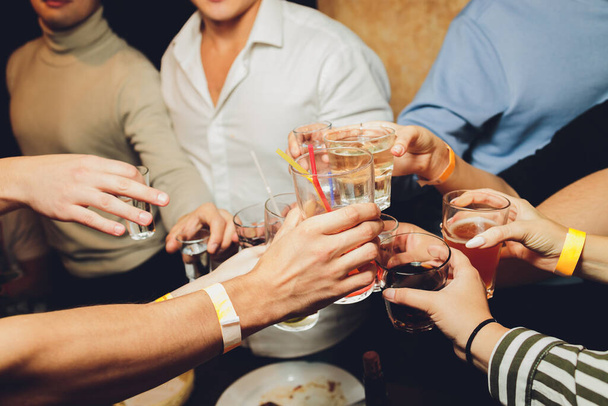 Close up shot of group of people clinking glasses with wine or champagne in front of bokeh background. older people hands. - Fotografie, Obrázek