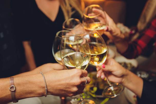 Close up shot of group of people clinking glasses with wine or champagne in front of bokeh background. older people hands. - Foto, Imagem