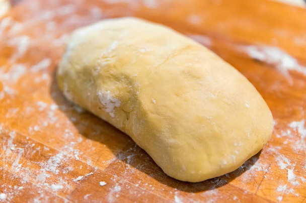 Сире тісто, покрите борошном на дерев'яній обробній дошці
 - Фото, зображення