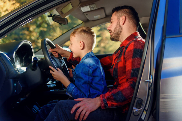 handsome father pointing on something while teaching teen son driving car - Fotoğraf, Görsel